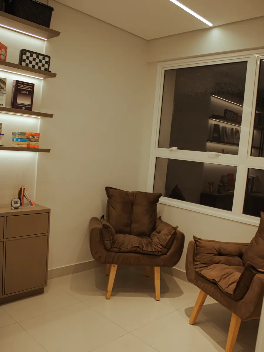 Sala de atendimento com poltronas e prateleiras de livros